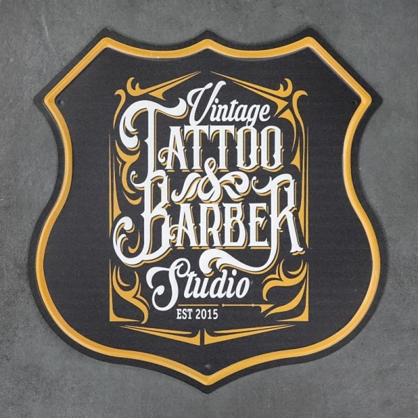 Kovová cedule ve tvaru štítu Tattoo&Barber